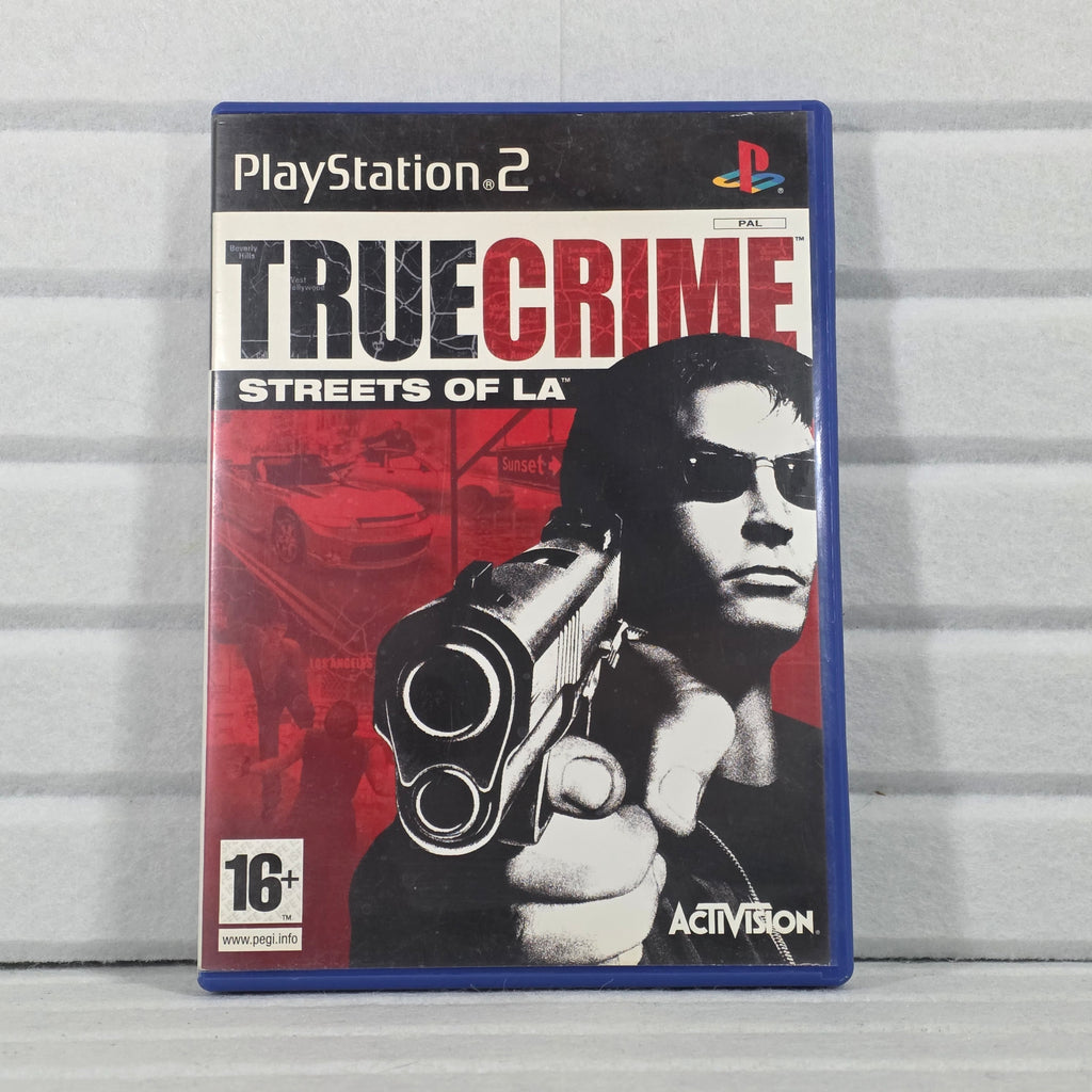 A PlayStation 2 game case for 'True Crime: Streets of LA' by Activision, featuring a red, black, and white cover with a portrait of a man holding a gun, photographed against a light gray paneled background.